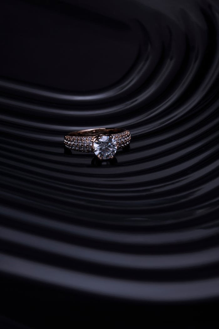 Close-up of a diamond ring with a dark, wavy background creating a luxurious and elegant atmosphere.