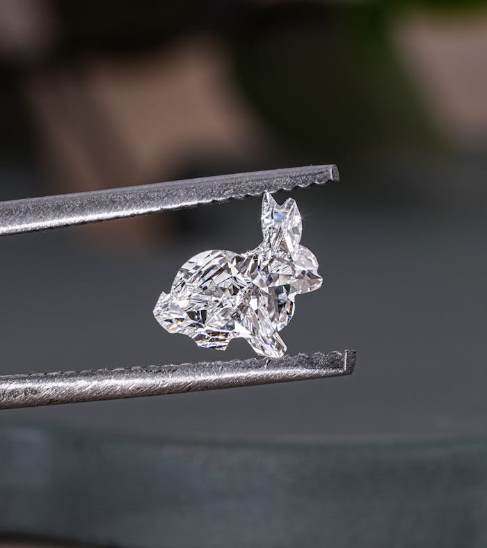 Close-up of a sparkling rabbit-shaped lab-grown diamond held by tweezers in Surat.