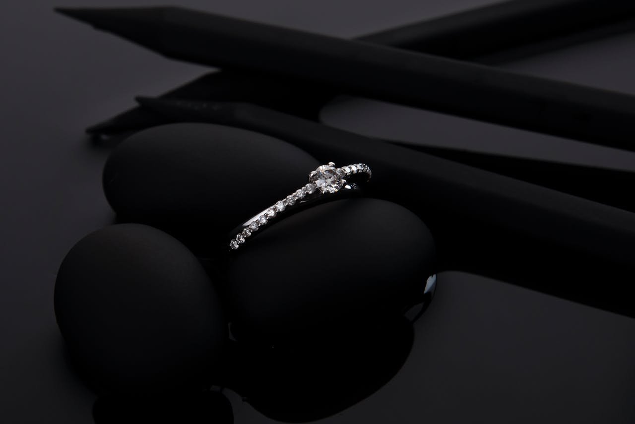 Sophisticated diamond engagement ring displayed stylishly on smooth black stones, perfect for luxury and jewelry themes.